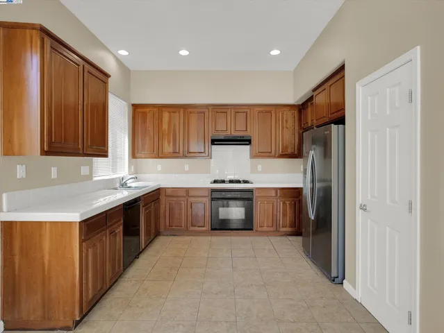 a kitchen with granite countertop a refrigerator and a stove top oven