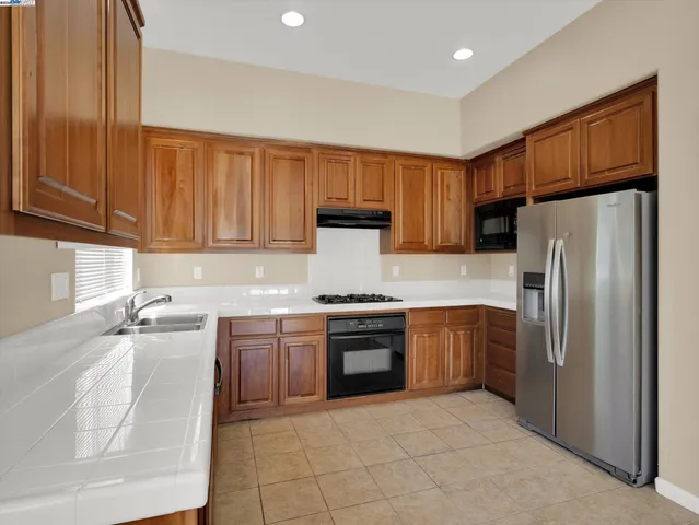 a kitchen with stainless steel appliances granite countertop a refrigerator stove and sink