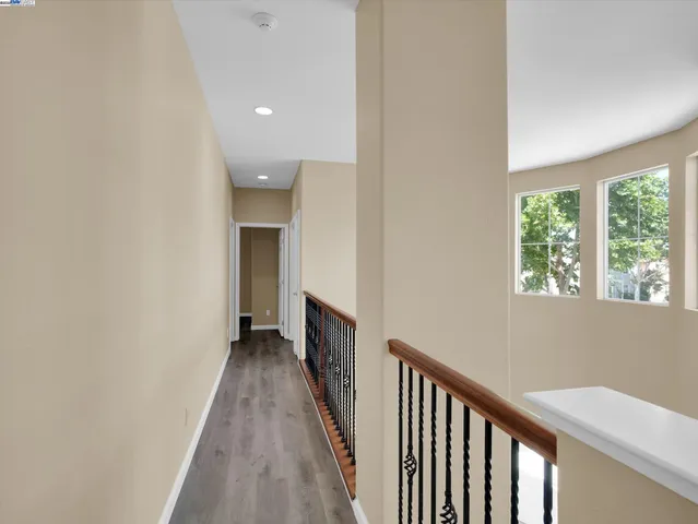 a view of a hallway with wooden floor and a bathroom