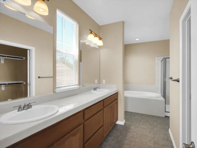a bathroom with a sink double vanity granite tub and a mirror