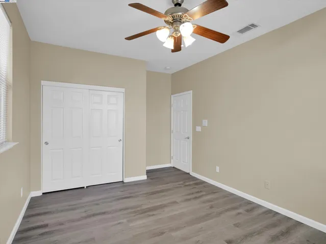 an empty room with wooden floor chandelier fan and closet area