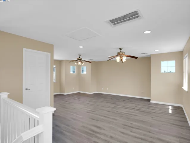 a view of empty room with wooden floor and fan
