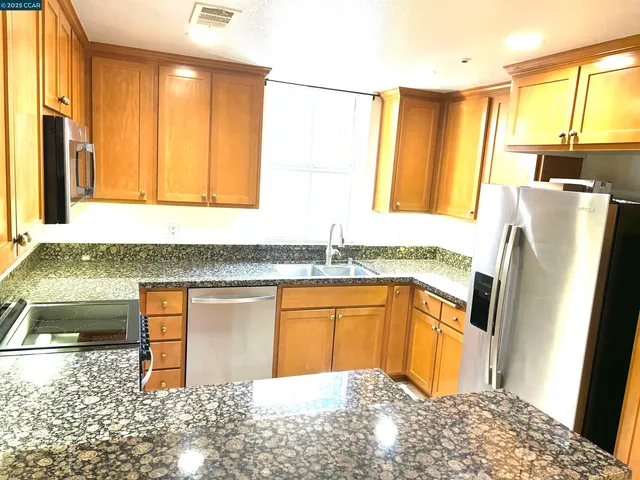 a kitchen with stainless steel appliances granite countertop a refrigerator and a sink