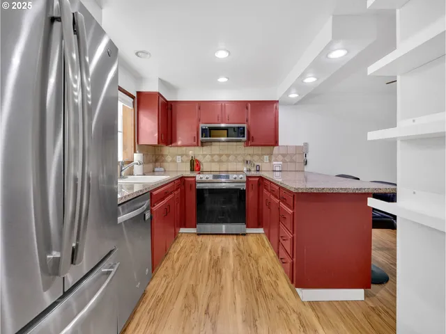 a kitchen with stainless steel appliances granite countertop a stove a sink dishwasher a refrigerator and a oven with wooden floor