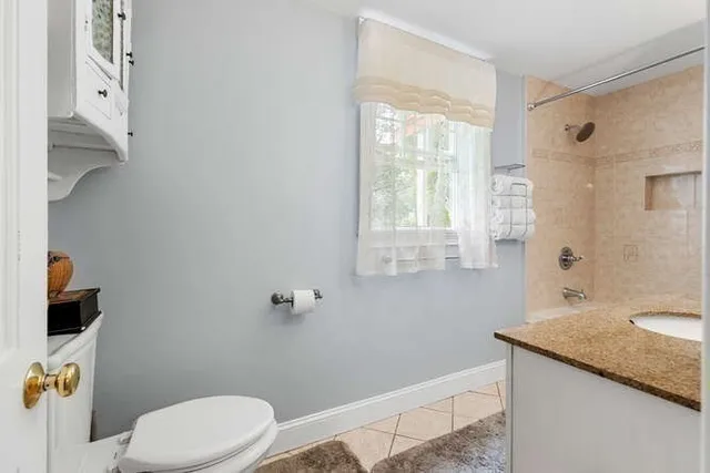 a bathroom with a granite countertop sink a toilet and shower