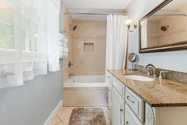 a bathroom with a granite countertop tub sink and mirror