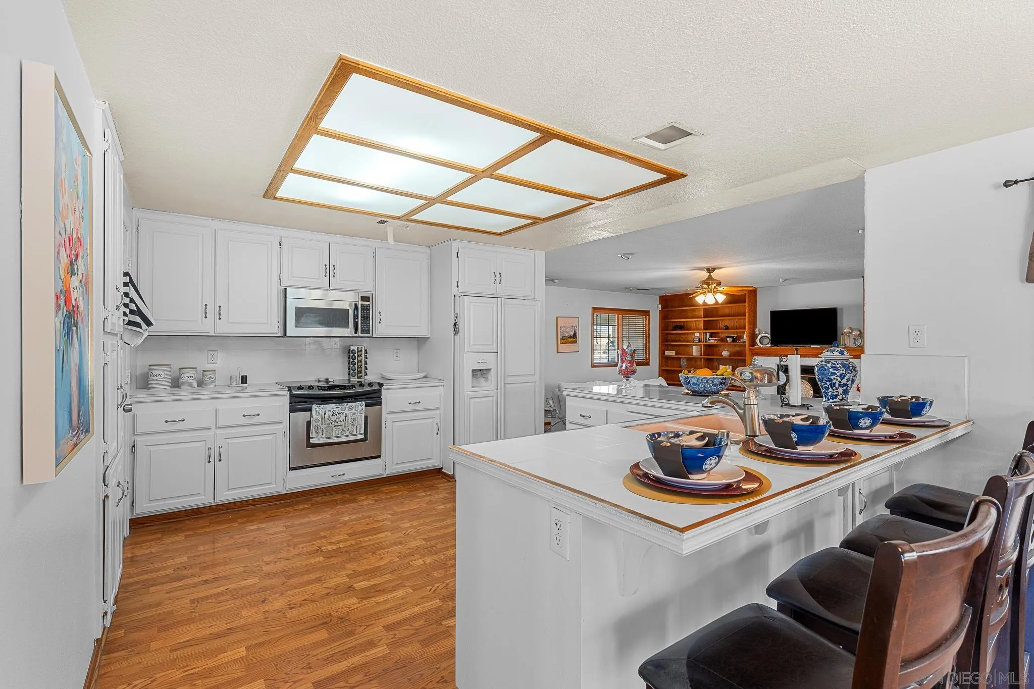 19775 Symeron Road Apple Valley, CA 92307 - Photo 18 of 73 a kitchen with stainless steel appliances kitchen island granite countertop a sink dishwasher stove and white cabinets with wooden floor