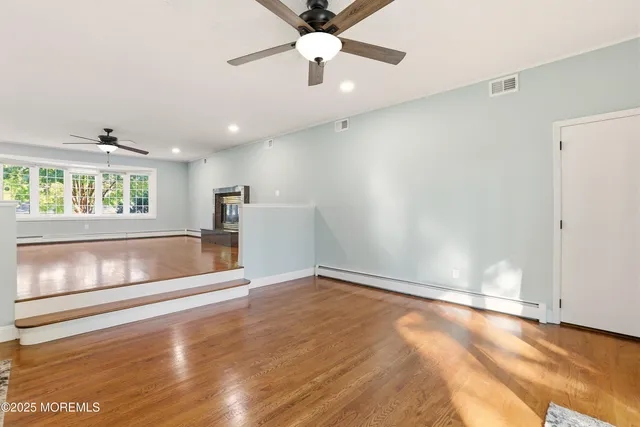 an empty room with wooden floor chandelier and windows