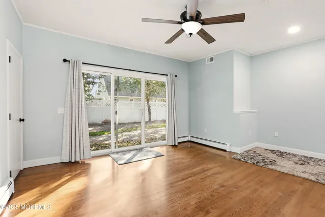 an empty room with wooden floor fan and windows
