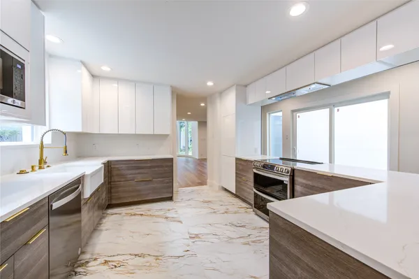 a view of an empty room with wooden floor and a kitchen