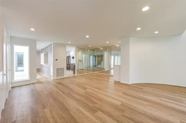 a view of an empty room with a window and wooden floor