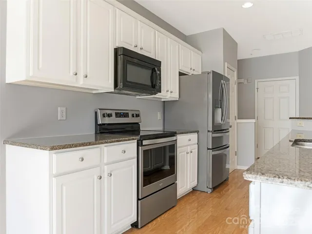 a kitchen with granite countertop white cabinets and stainless steel appliances