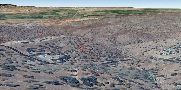a view of a dry yard with mountains in the background