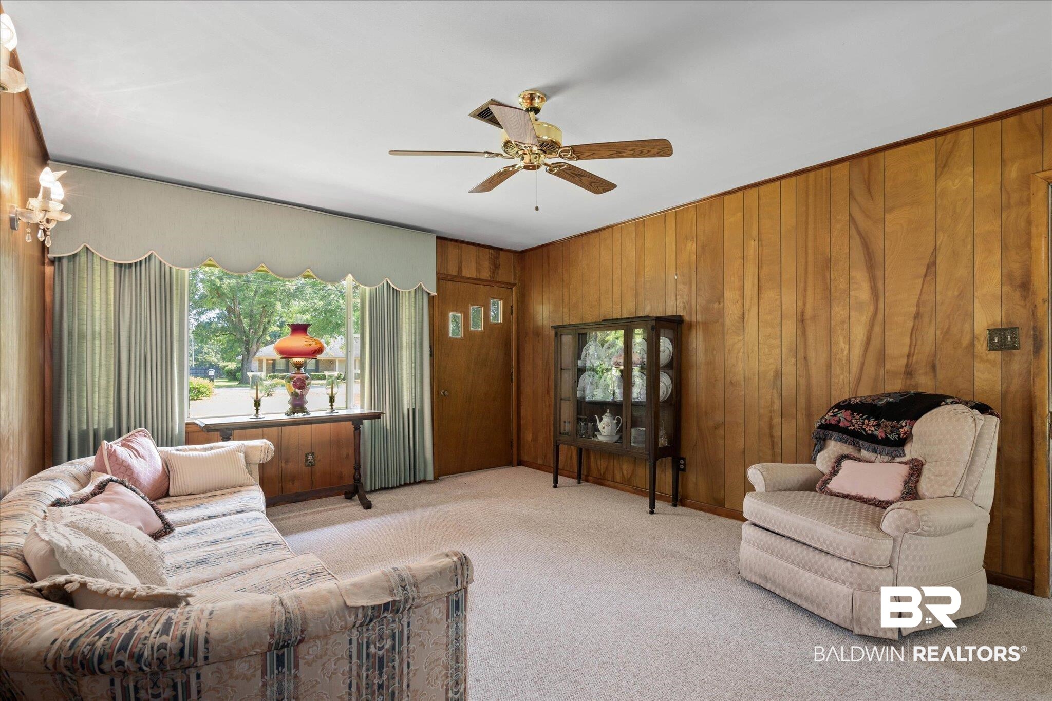 423 First Avenue Saraland, AL 36571 - Photo 3 of 20 Carpeted living area with healthy amount of natural light, a ceiling fan, and wooden walls