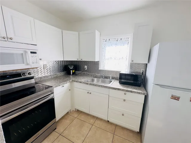 a kitchen with granite countertop white cabinets and white appliances