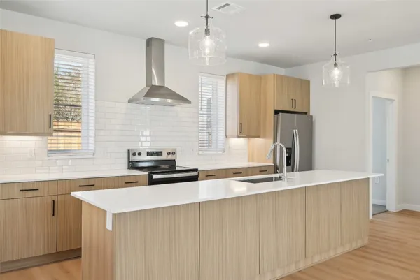 a kitchen with stainless steel appliances granite countertop a sink a stove a refrigerator and island with wooden floor