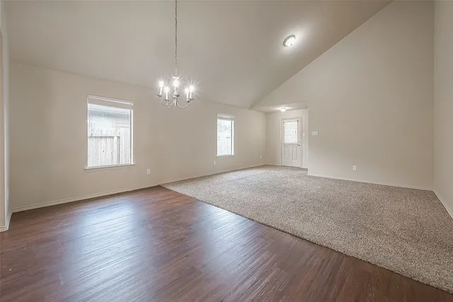 an empty room with wooden floor and chandelier