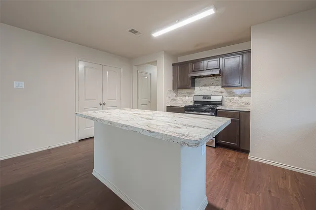 a kitchen with cabinets wooden floor and stainless steel appliances