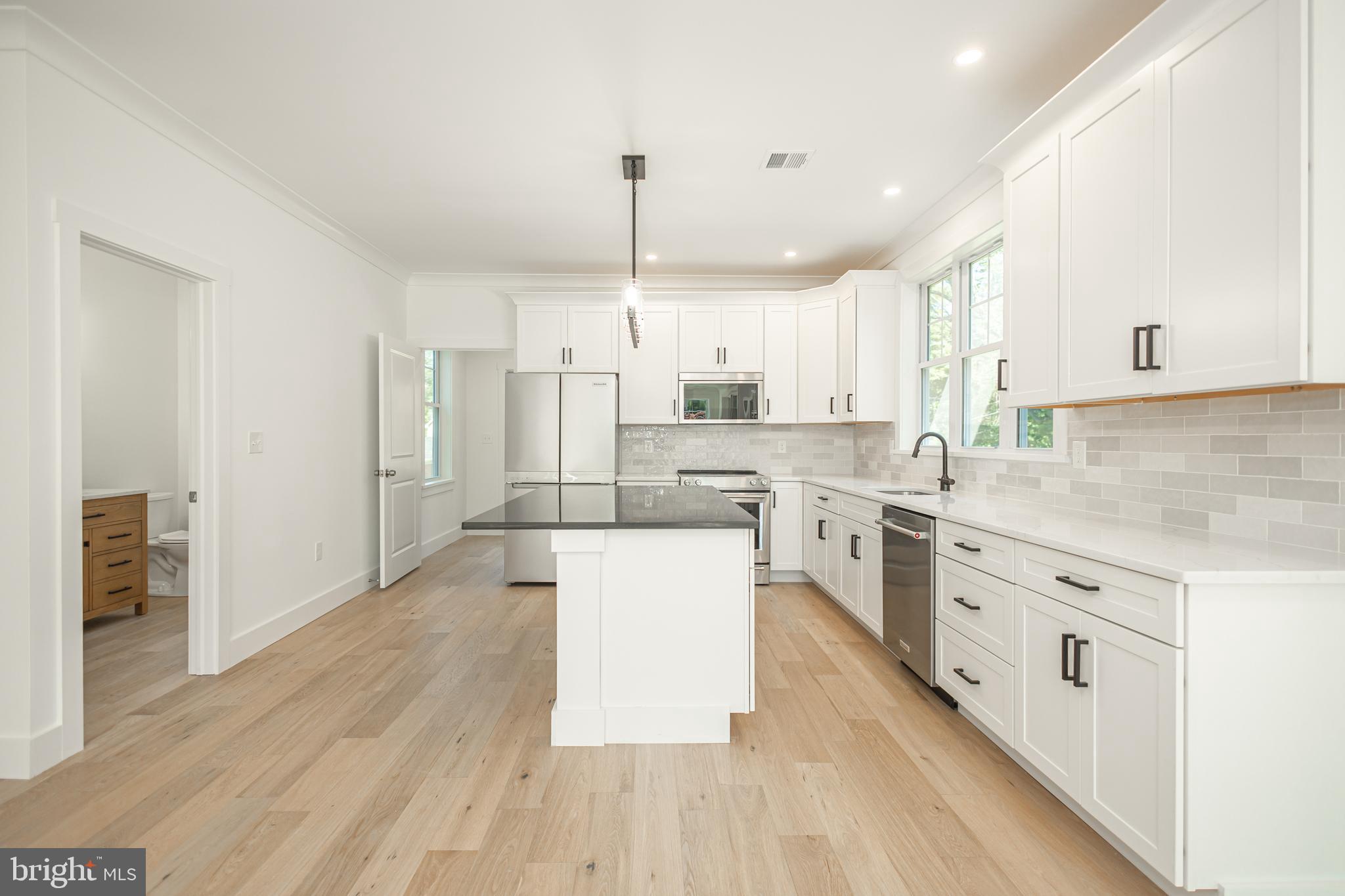 1764 River Road Upper Black Eddy, PA 18972 - Photo 8 of 37 a large kitchen with stainless steel appliances a stove a sink dishwasher a refrigerator white cabinets and wooden floor next to a window