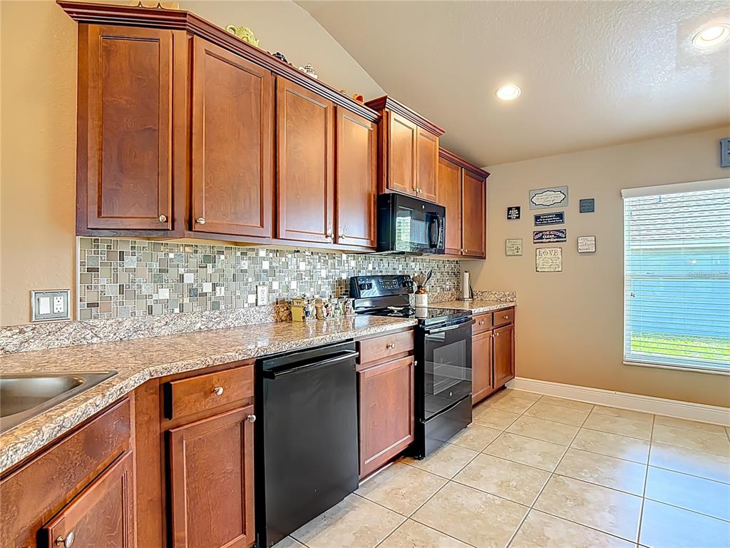 1170 Legatto Loop Dundee, FL 33838 - Photo 14 of 38 a kitchen with stainless steel appliances granite countertop a sink stove and refrigerator