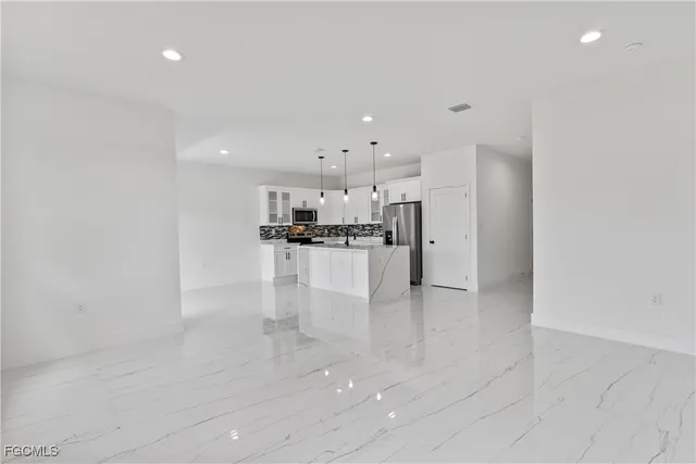 a kitchen with stainless steel appliances kitchen island granite countertop a refrigerator and a stove top oven