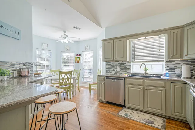 a kitchen with stainless steel appliances granite countertop a sink a stove a window and cabinets