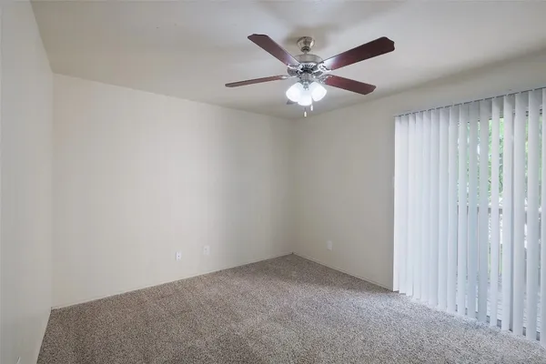 a view of an empty room and chandelier fan