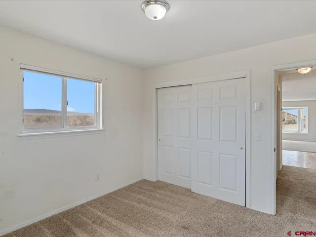 a view of an empty room with closet and a window
