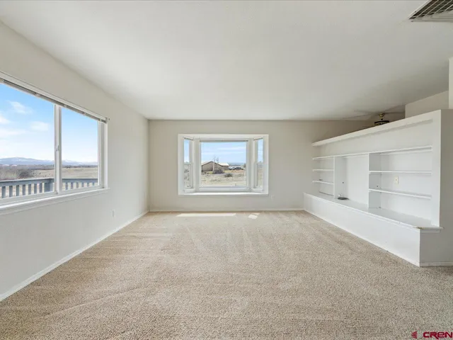 an empty room with windows and cabinet