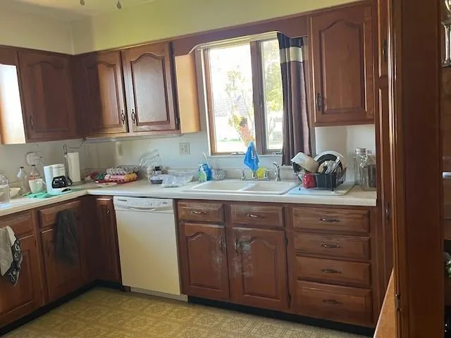 a kitchen with granite countertop wooden cabinets a sink and dishwasher with wooden floor