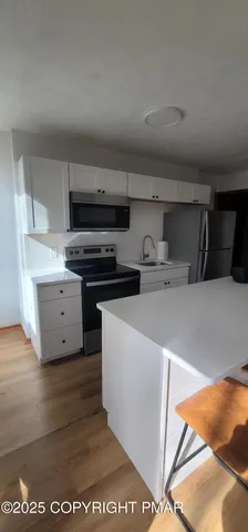 a living room with stainless steel appliances kitchen island granite countertop a refrigerator and a stove top oven