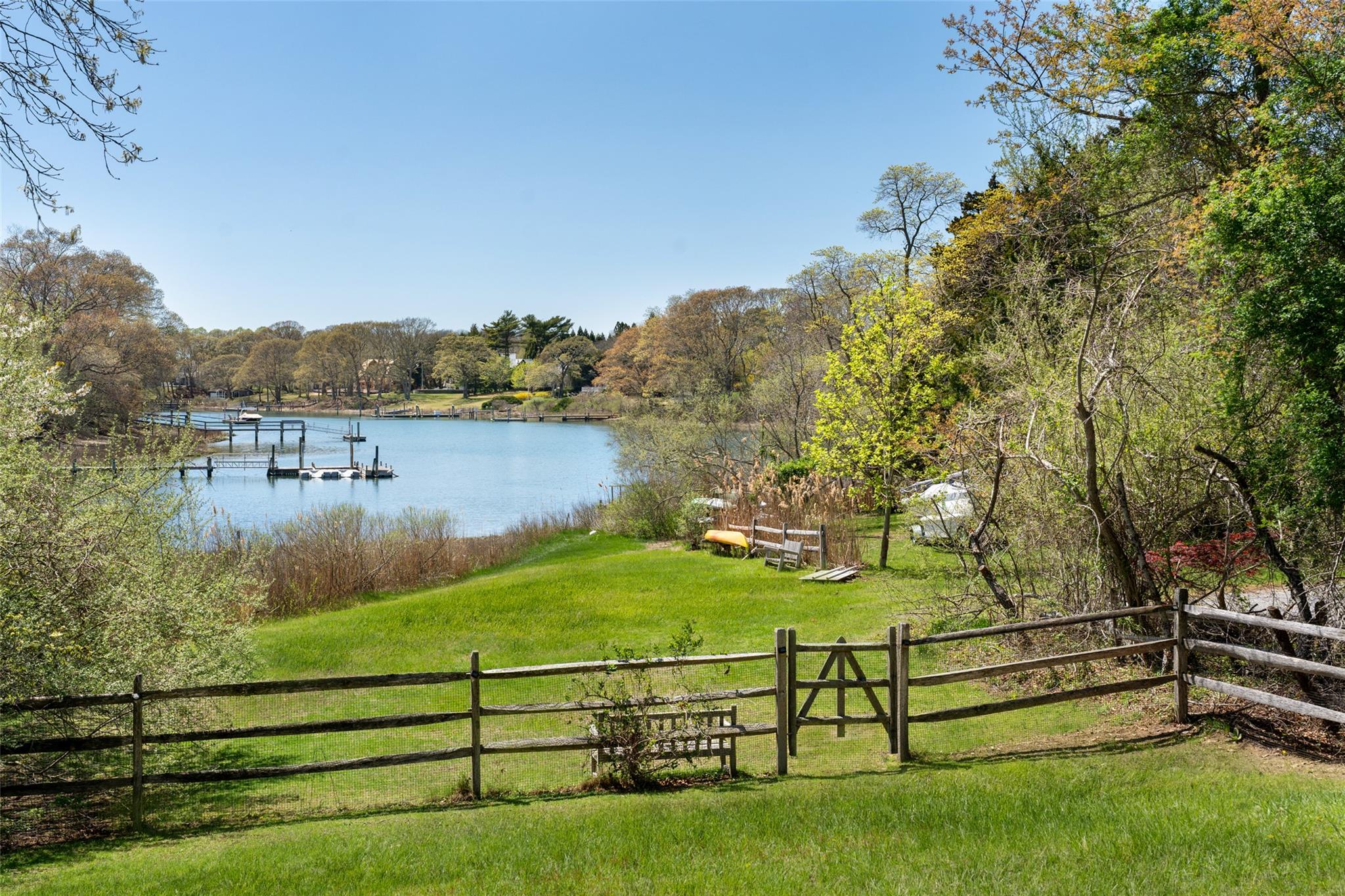 View of yard with a water view, fence, a forest view, and a dock