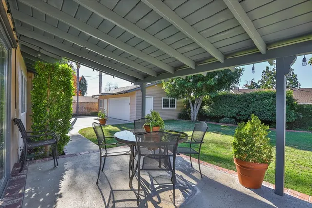 a view of patio with table and chairs potted plants and floor to ceiling window with wooden roof