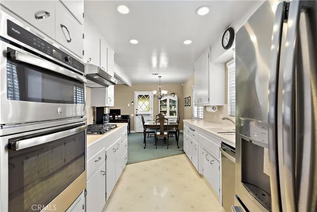 a kitchen with stainless steel appliances kitchen island granite countertop a refrigerator a sink dishwasher a stove and a dining table with wooden floor