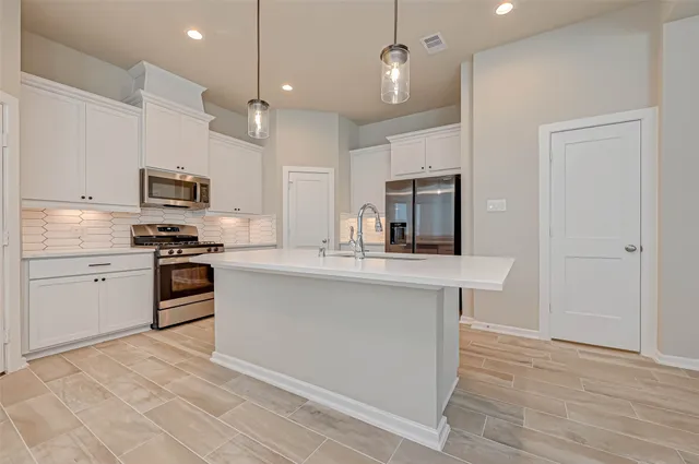 a kitchen with granite countertop a stove a sink and a refrigerator
