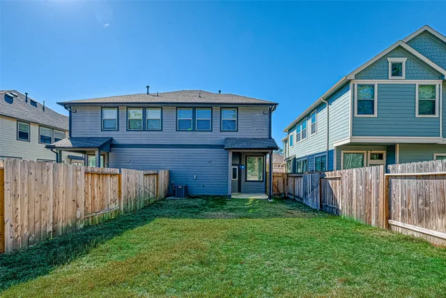 a view of a wooden house with a yard and wooden fence