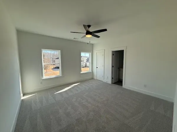 an empty room with windows and a ceiling fan