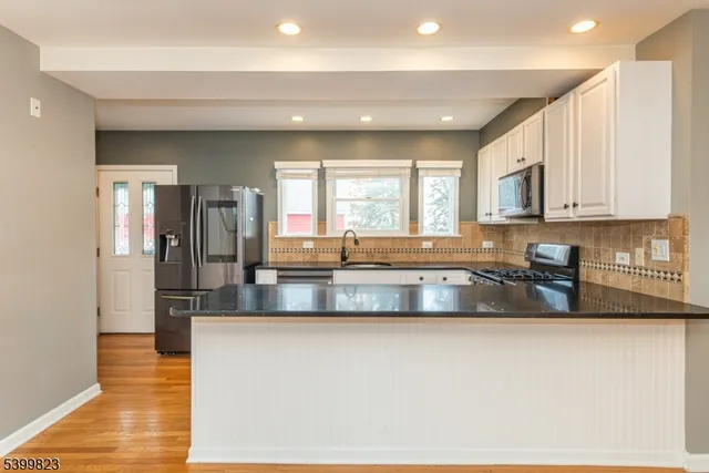 a large kitchen with granite countertop a large window and stainless steel appliances