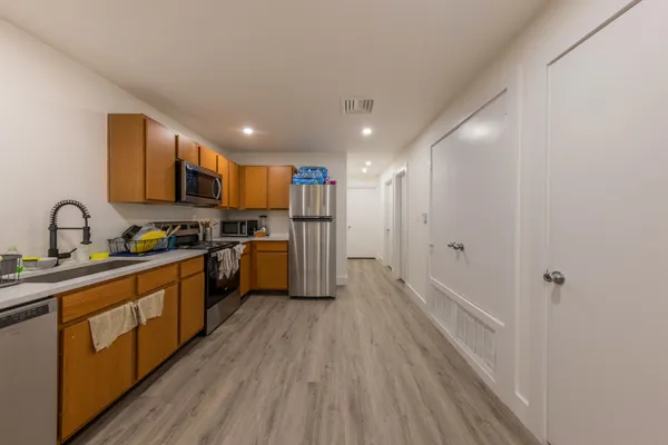 a kitchen with stainless steel appliances granite countertop a refrigerator a sink dishwasher a stove with wooden cabinets and floor