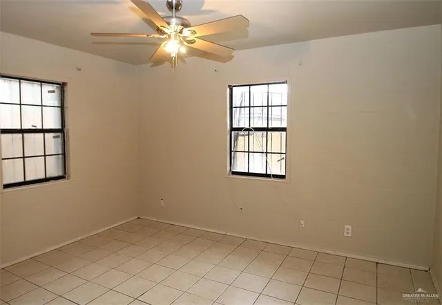 an empty room with windows and fan