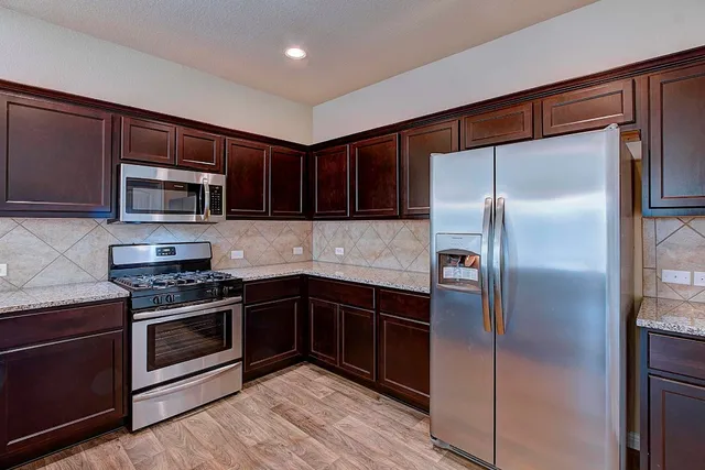 a kitchen with granite countertop a refrigerator and a stove top oven