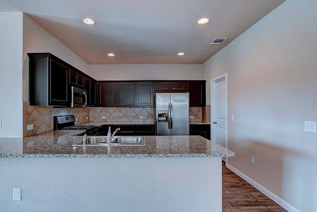a large kitchen with granite countertop a large counter top stainless steel appliances and cabinets