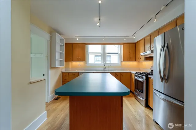 a kitchen with stainless steel appliances a refrigerator sink and wooden floor