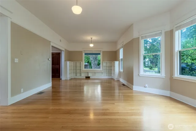 a view of an empty room with window and wooden floor