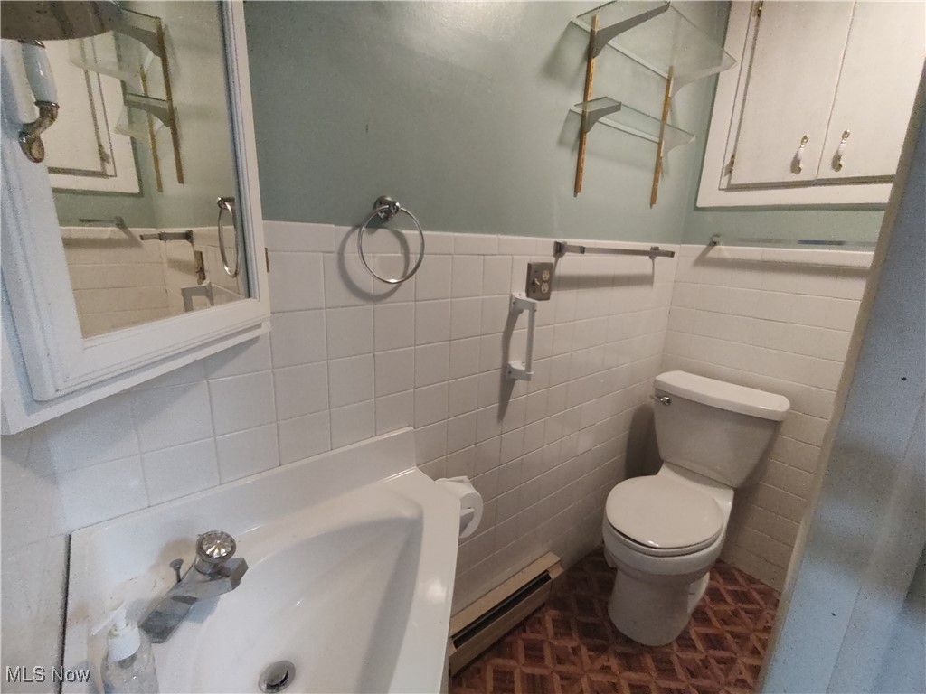 5704 Middle Ridge Road Madison, OH 44057 - Photo 34 of 50 Bathroom with a baseboard heating unit, a wainscoted wall, toilet, and tile walls