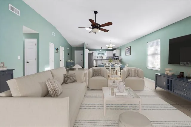 a living room with furniture a flat screen tv and kitchen view