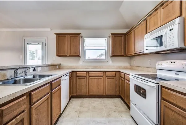 a kitchen with cabinets appliances a sink and a window