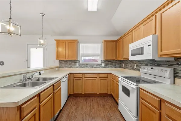 a kitchen with a sink stove cabinets and wooden floor