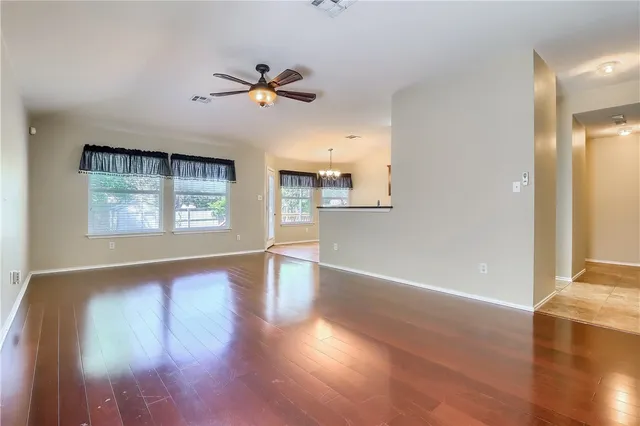 an empty room with wooden floor fan and windows