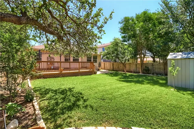 a view of a backyard with large trees and wooden fence